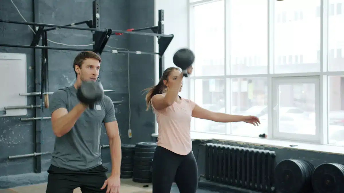 Dos deportistas entrenando sentadillas con pesas rusas en un gimnasio