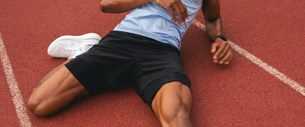 Atleta realiza un estiramiento de pierna en una pista de atletismo