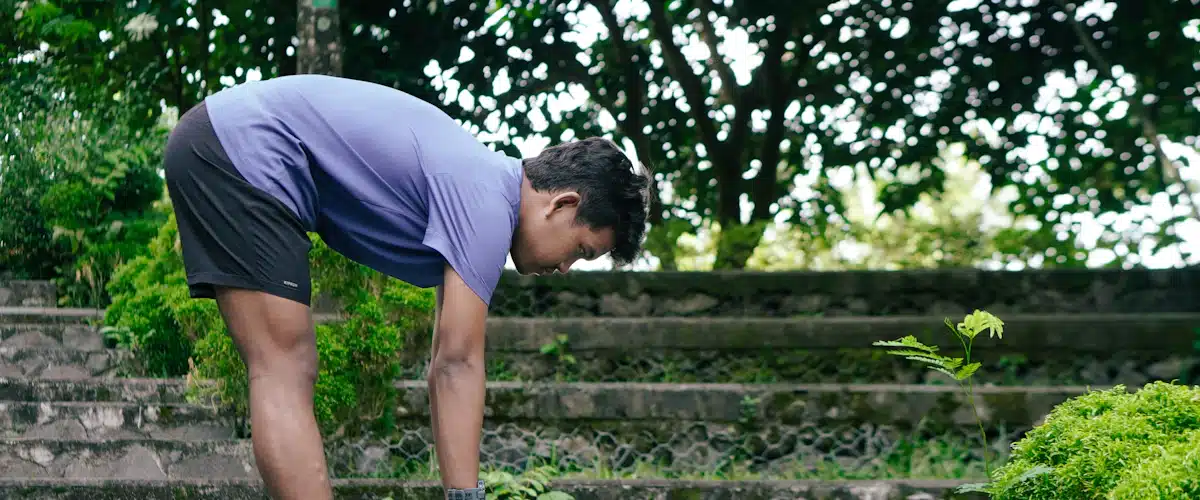 Deportista estira las piernas sobre escalones de piedra en un parque