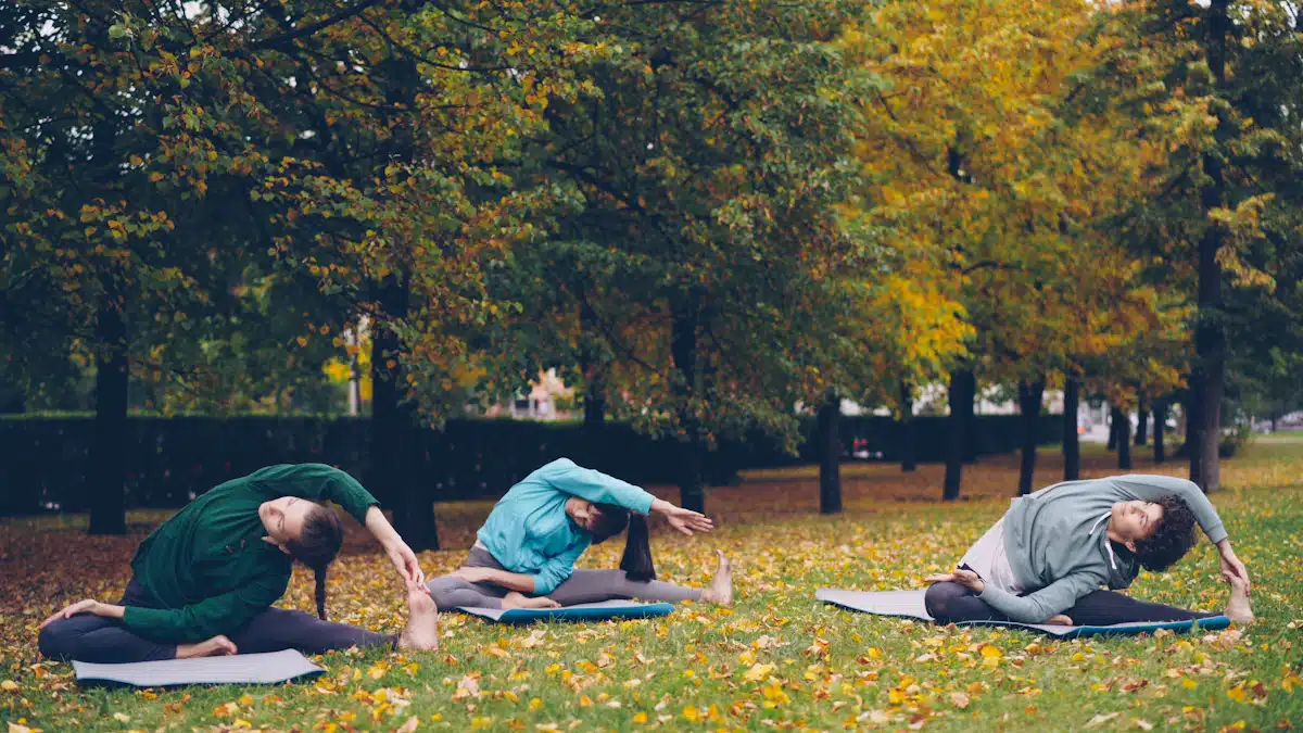 Tres personas realizan estiramientos sobre esterillas al aire libre entre árboles