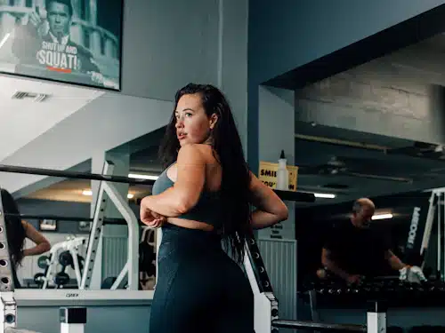 Atleta de fuerza muestra su musculatura junto a una máquina de gimnasio