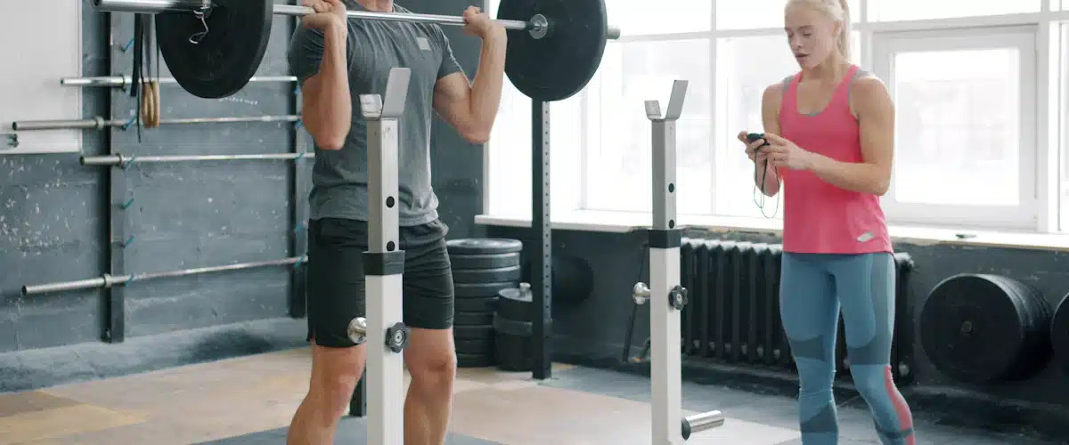 Atleta practicando fuerza con barra bajo la supervisión de su entrenadora
