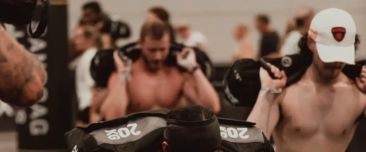 Atleta realizando una zancada cargada con saco de arena en gimnasio