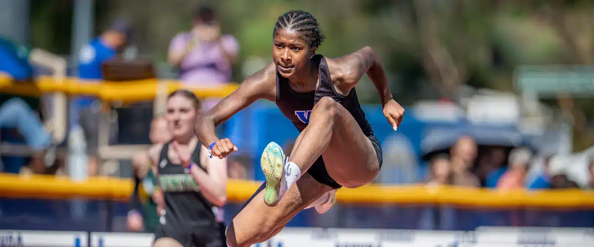 Atleta supera una valla durante una carrera de velocidad en pista