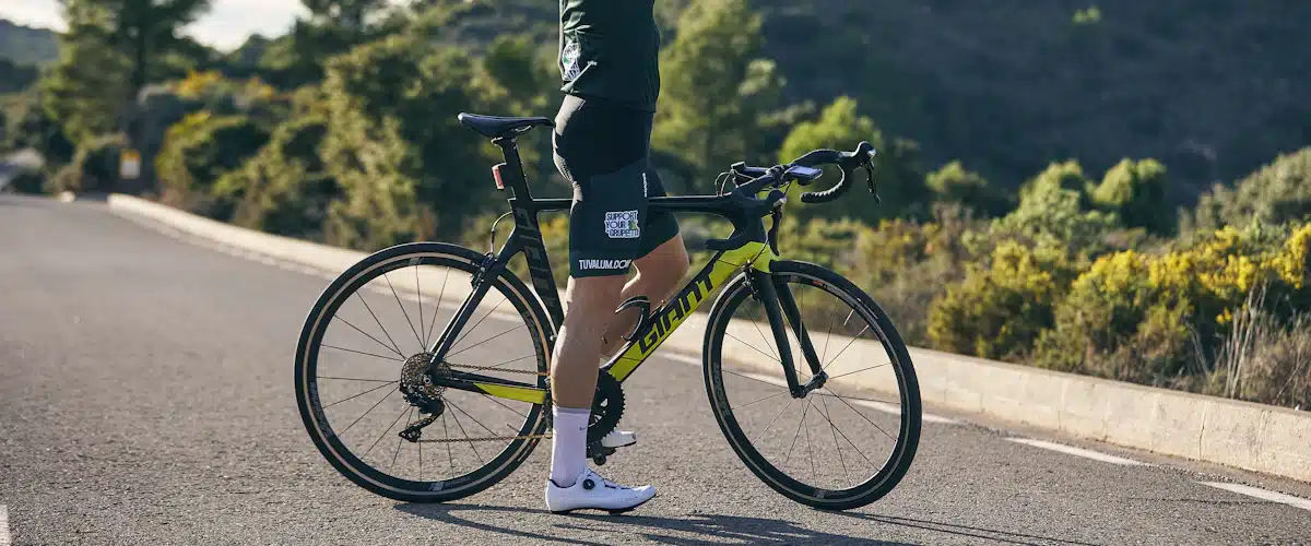 Ciclista con casco bebiendo agua junto a su bicicleta de carretera