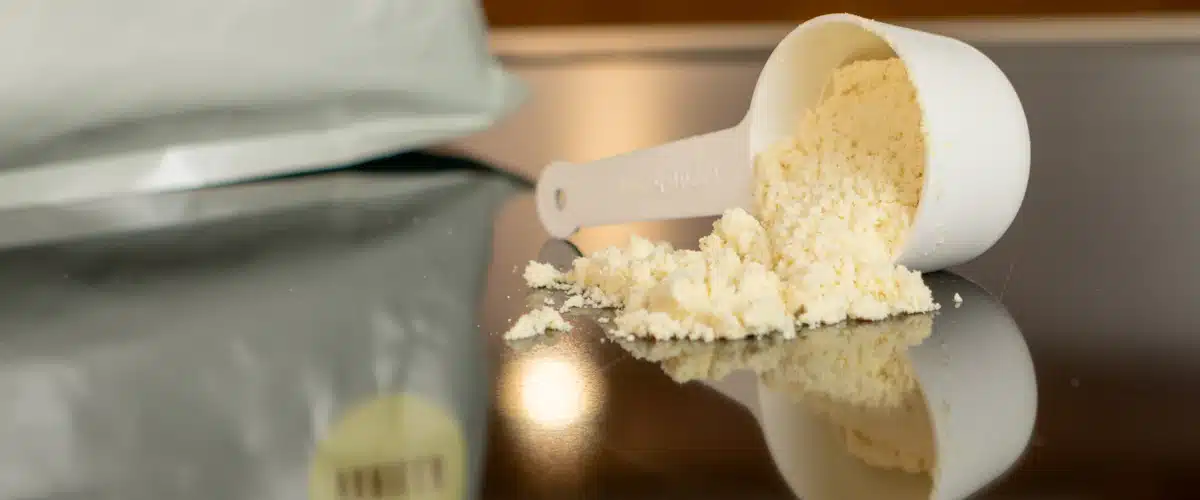 Cuchara con proteína en polvo de vainilla preparada para mezclar