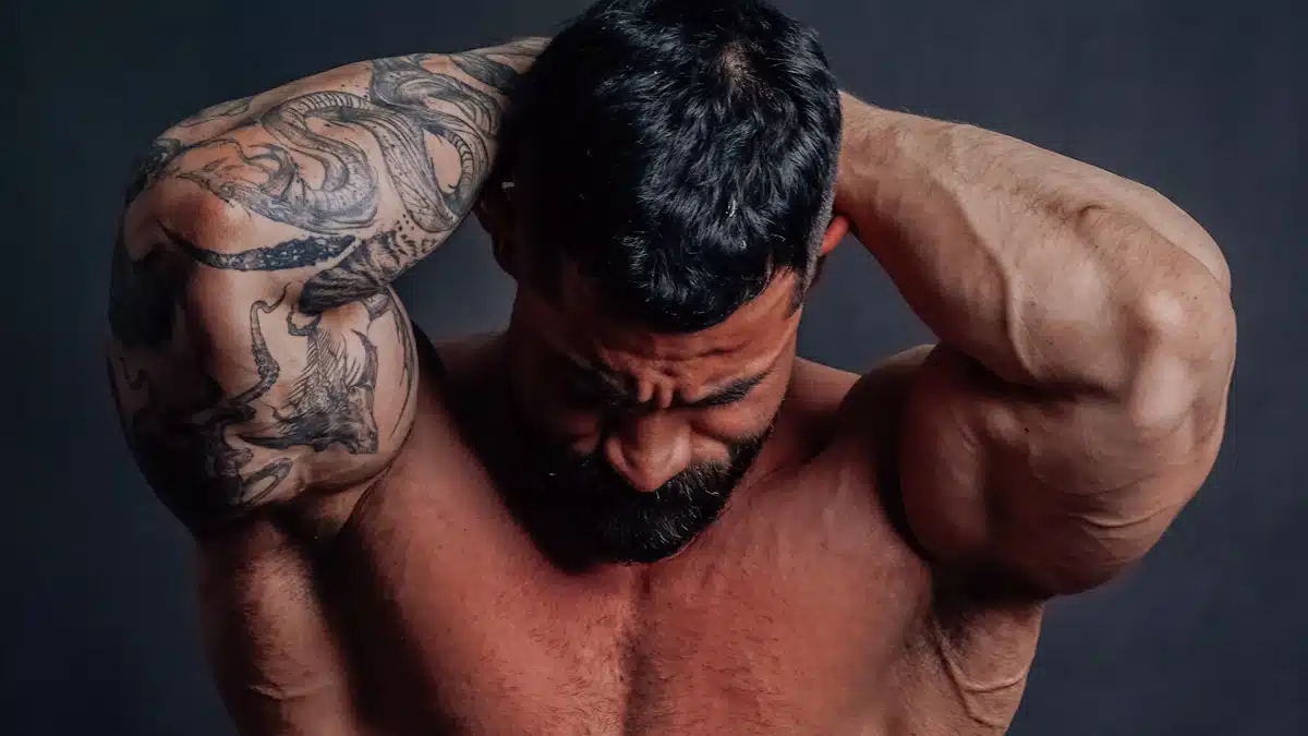 Culturista de musculatura desarrollada posando ante fondo oscuro para fotografía deportiva