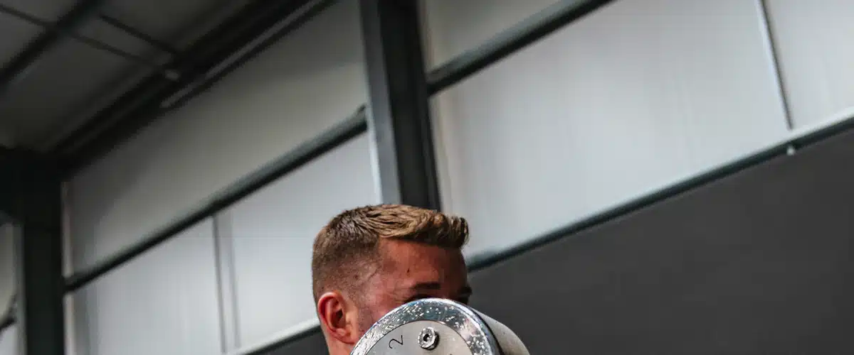 Culturista realizando curl de bíceps frente al espejo del gimnasio