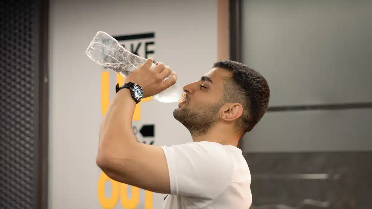 Deportista bebiendo agua durante una pausa del entrenamiento en gimnasio