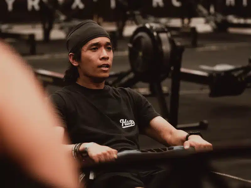 Deportista entrenando sobre remo ergómetro en sala de acondicionamiento físico