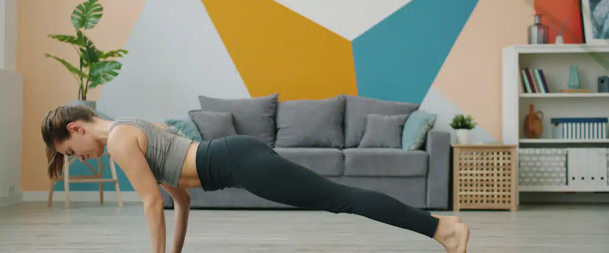Deportista manteniendo una plancha abdominal sobre esterilla en su salón
