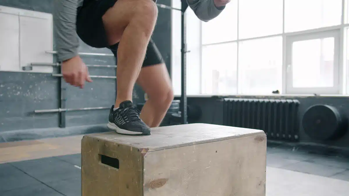 Deportista realiza un salto pliométrico sobre un cajón en el gimnasio