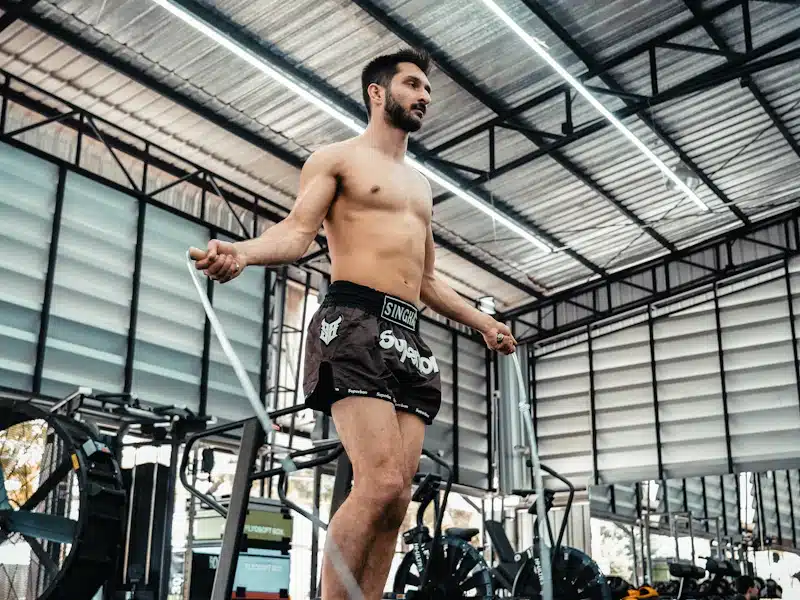 Deportista saltando cuerda con postura compacta y ritmo controlado en gimnasio