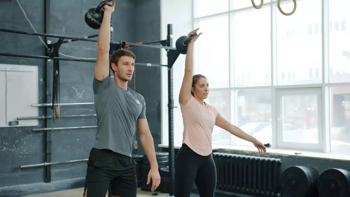 Dos deportistas realizan ejercicios con kettlebell en un gimnasio equipado