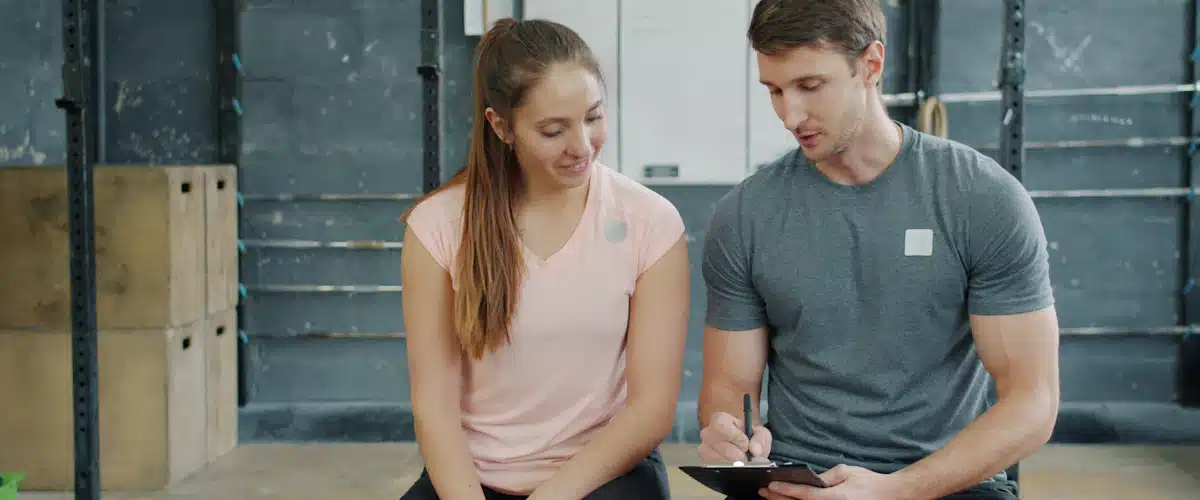 Entrenador y deportista revisando juntos su planificación física en gimnasio