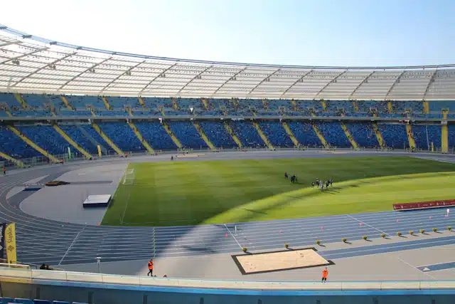 Estadio con gradas azules, campo de césped y pista de atletismo