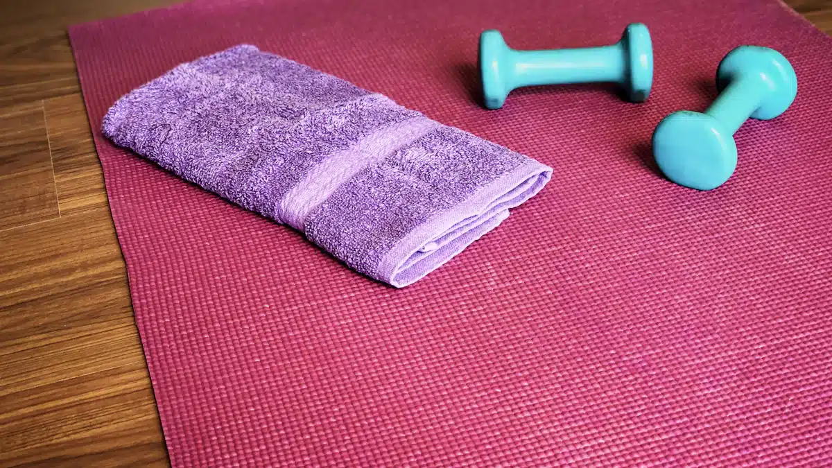 Esterilla, mancuernas y toalla preparadas para un entrenamiento en casa