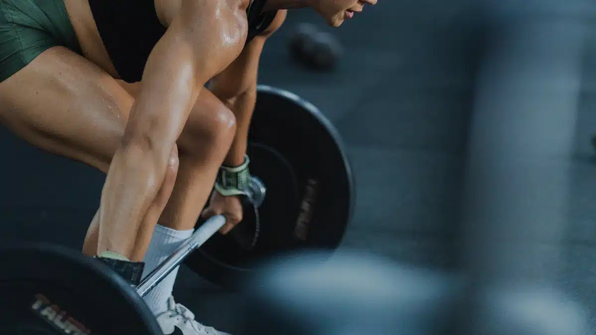 Mujer deportista entrenando con barra y discos en un gimnasio