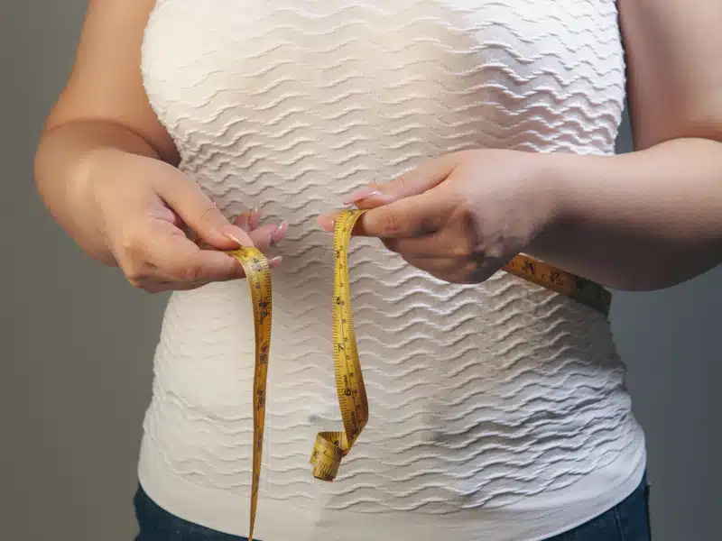 Mujer realiza una medición corporal antes de calcular su gasto energético