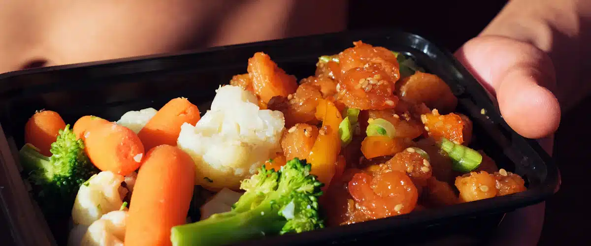 Persona sostiene un recipiente con comida preparada rica en vegetales