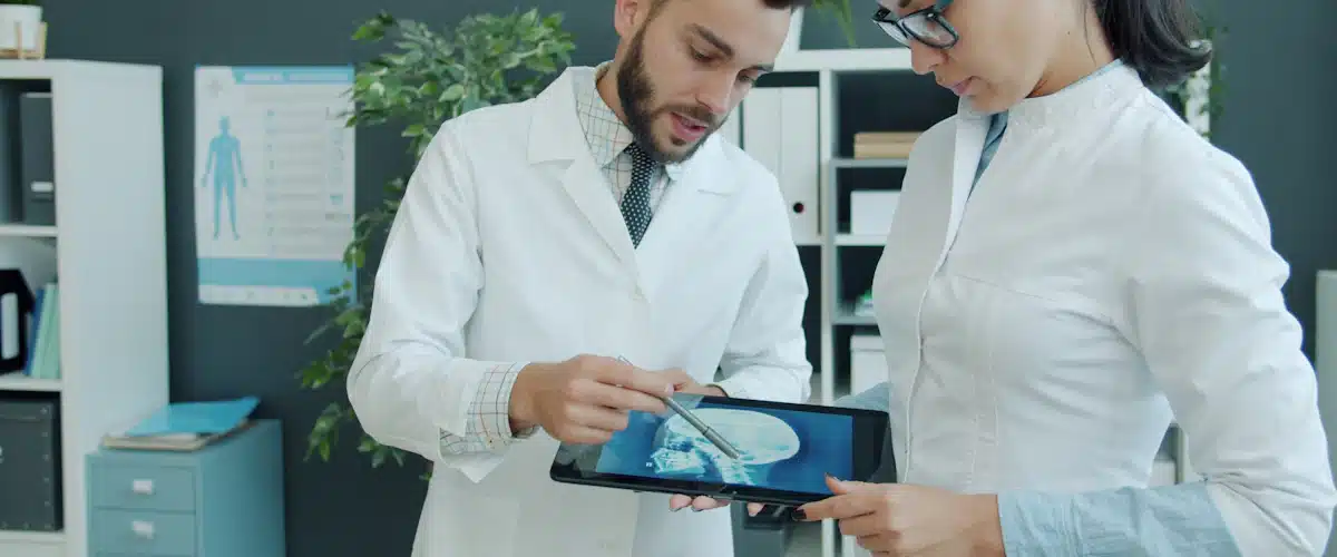 Profesionales sanitarios analizan imágenes médicas en una tableta durante consulta